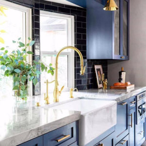 Brass Waterstone faucet in kitchen with blue cabinetry. 